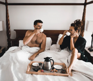 man and lady drinking coffee in bed